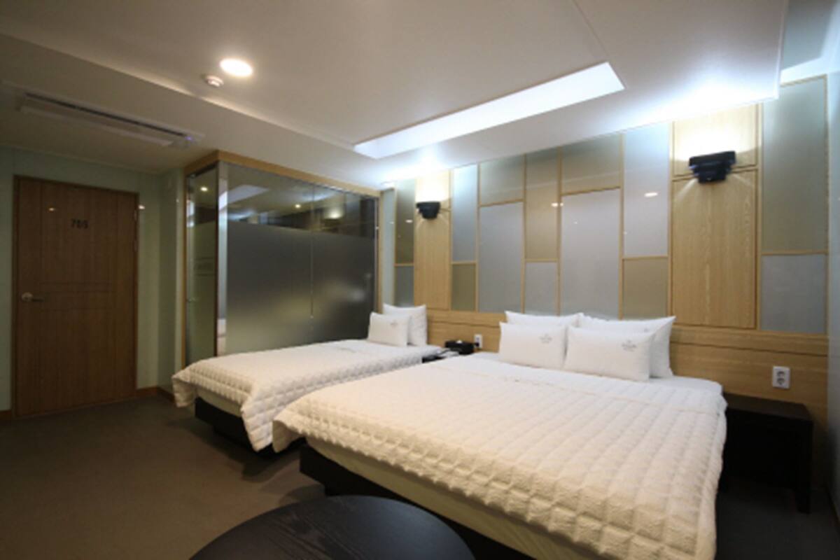 A hotel room with two beds, a large mirror, and a wooden wardrobe.