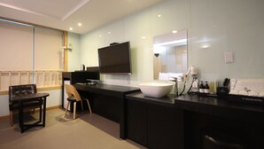 Une salle de bain d’hôtel moderne, dotée d’un grand miroir, d’un lavabo et d’un téléviseur.