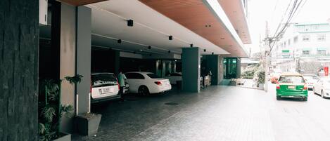 The entrance to the Spenza Hotel with a modern design, featuring a signboard and a covered parking area.