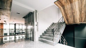 A modern interior with a staircase, glass railings, and a view of the city. - Spenza Hotel (Bangkok)