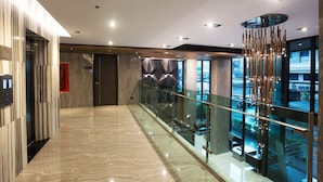 A modern hotel lobby with a marble floor, glass railing, and a view of the street outside. - Spenza Hotel (Bangkok)