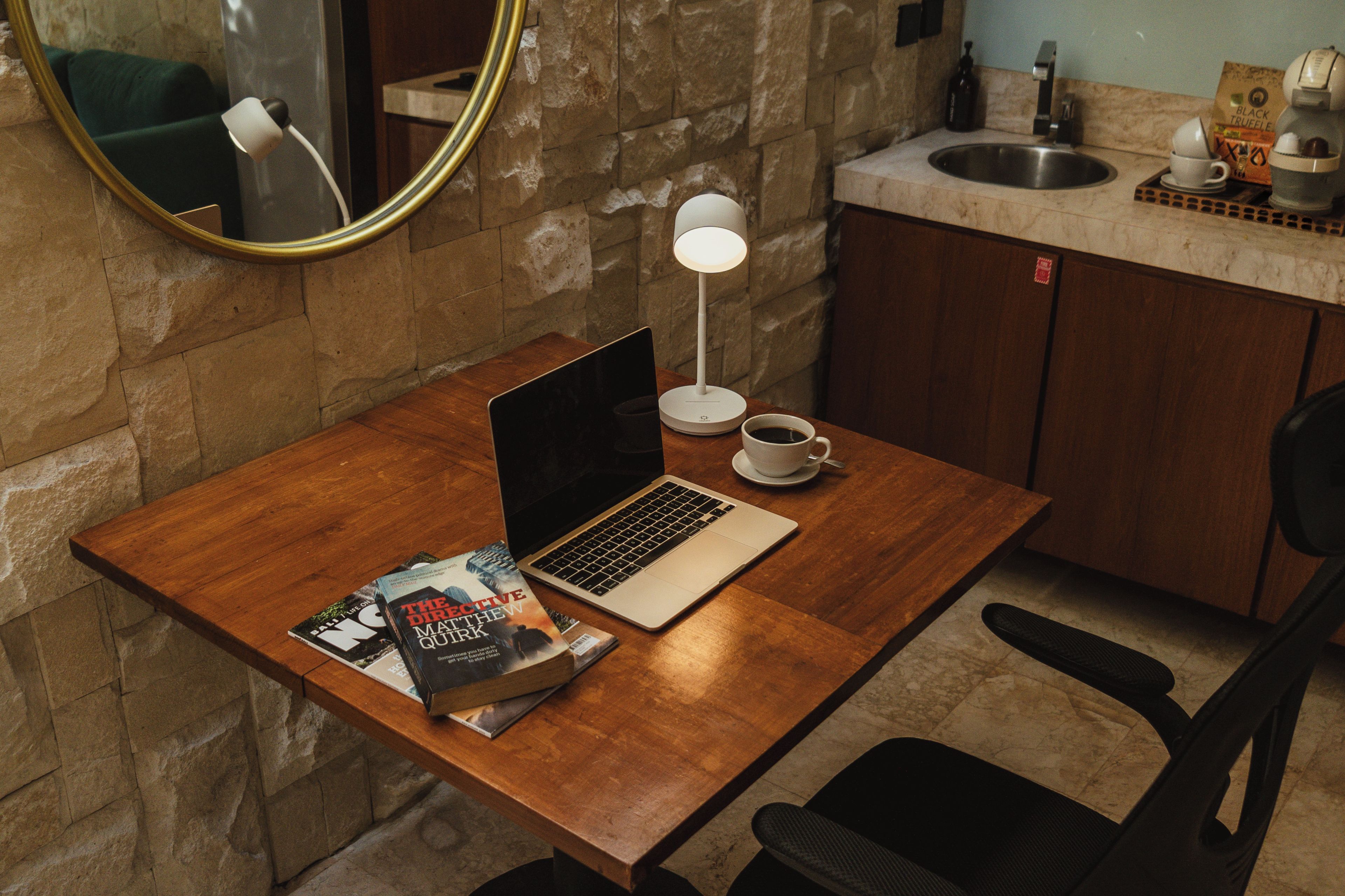 Un escritorio de madera con una computadora portátil, una taza de café y una revista.