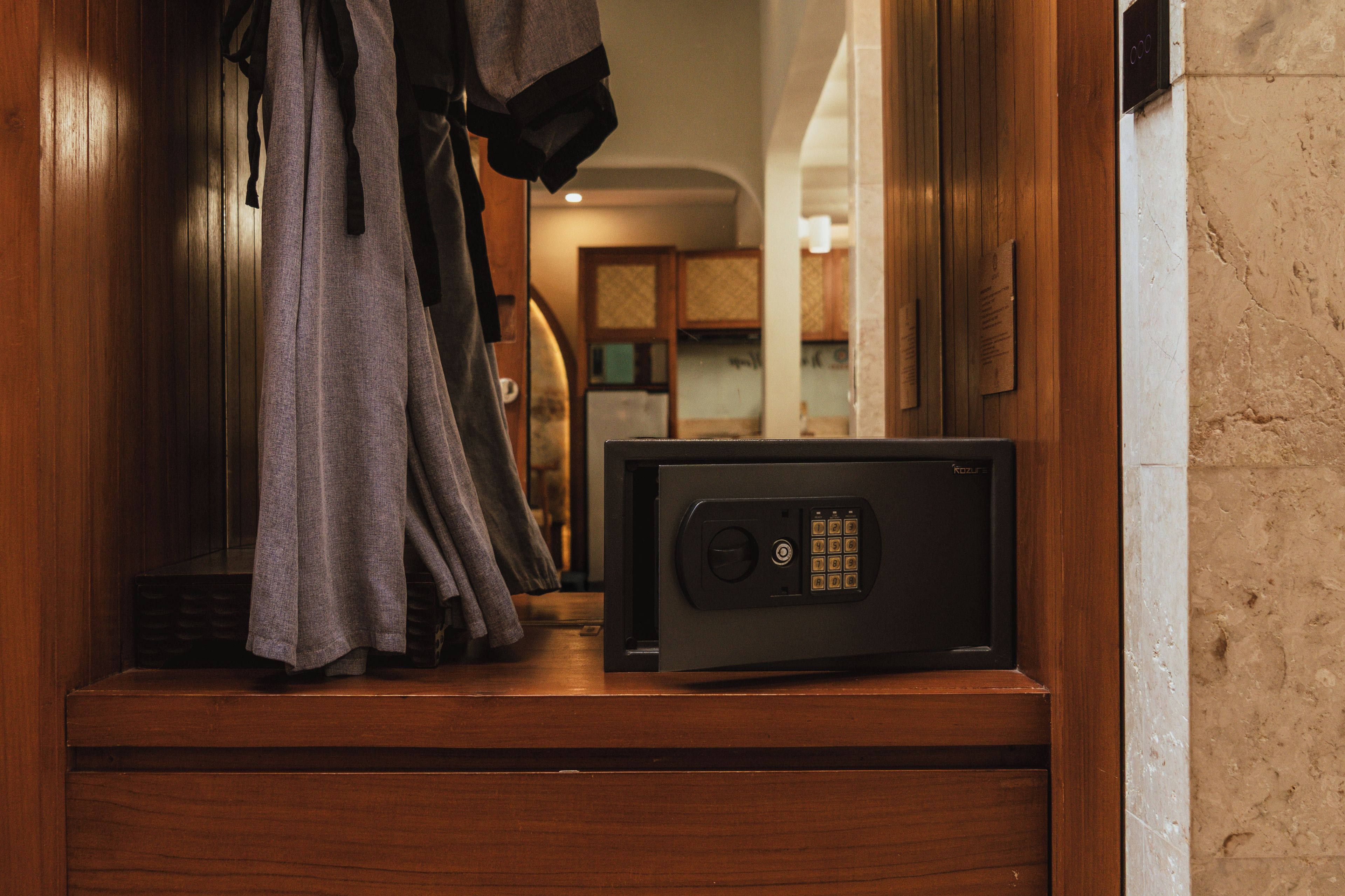 A secure safe on a wooden counter with a robe hanging nearby.