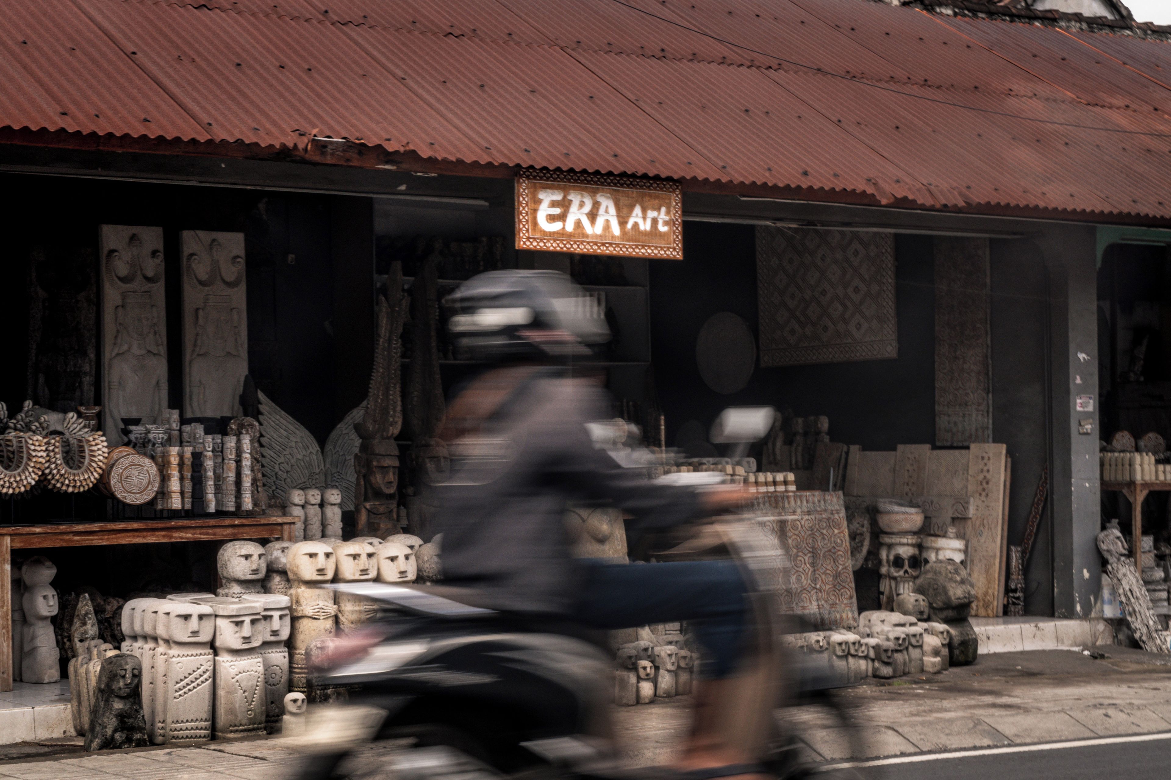 A storefront with a sign that reads 'ERA Art' and various sculptures and artifacts displayed outside.