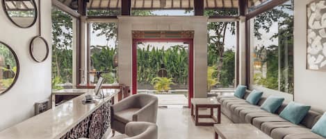 A modern interior with a bar area, seating, and a view of greenery.