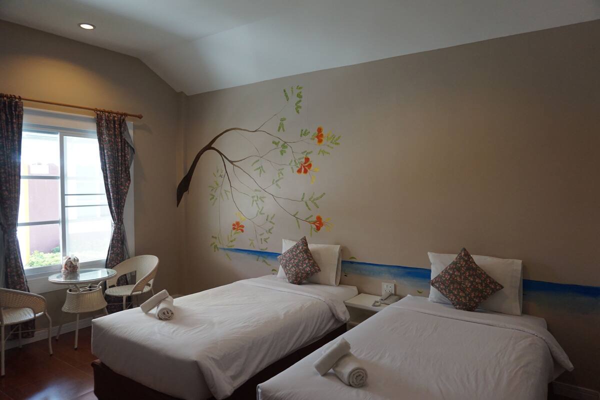 A hotel room with two beds, a small table, and chairs.
