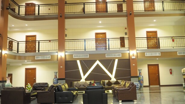 A spacious lobby with a high ceiling, multiple floors, and a central seating area with sofas and armchairs. - Suksomboon Hotel (Surat Thani)