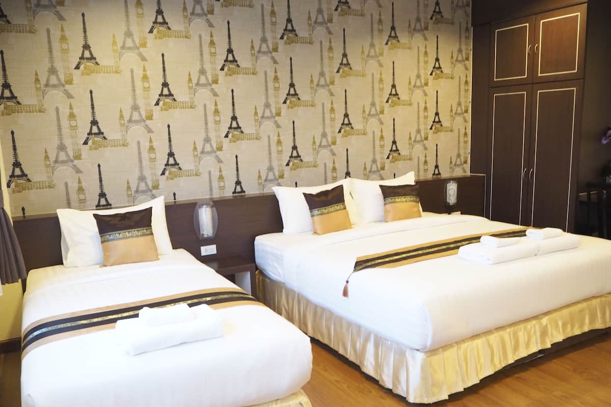 Een hotelkamer met twee bedden, een houten vloer en behangpapier met de Eiffeltoren.