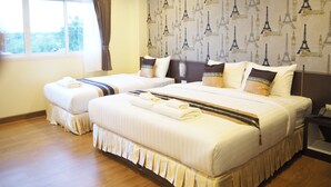 A hotel room with two beds, a large window with curtains, and a wall decorated with Eiffel Tower patterns. - Suksomboon Hotel (Surat Thani)