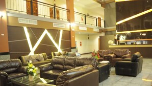 A lobby with leather sofas, a glass coffee table, and a reception desk. - Suksomboon Hotel (Surat Thani)