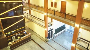 A multi-level hotel lobby with a reception desk, a staircase, and a view of the lower floors. - Suksomboon Hotel (Surat Thani)
