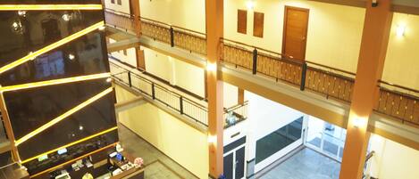 Un vestíbulo de hotel de varios niveles con una recepción, una escalera y vistas a los pisos inferiores.
