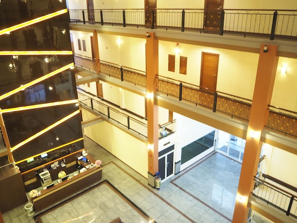 A multi-level hotel lobby with a reception desk, a staircase, and a view of the lower floors.