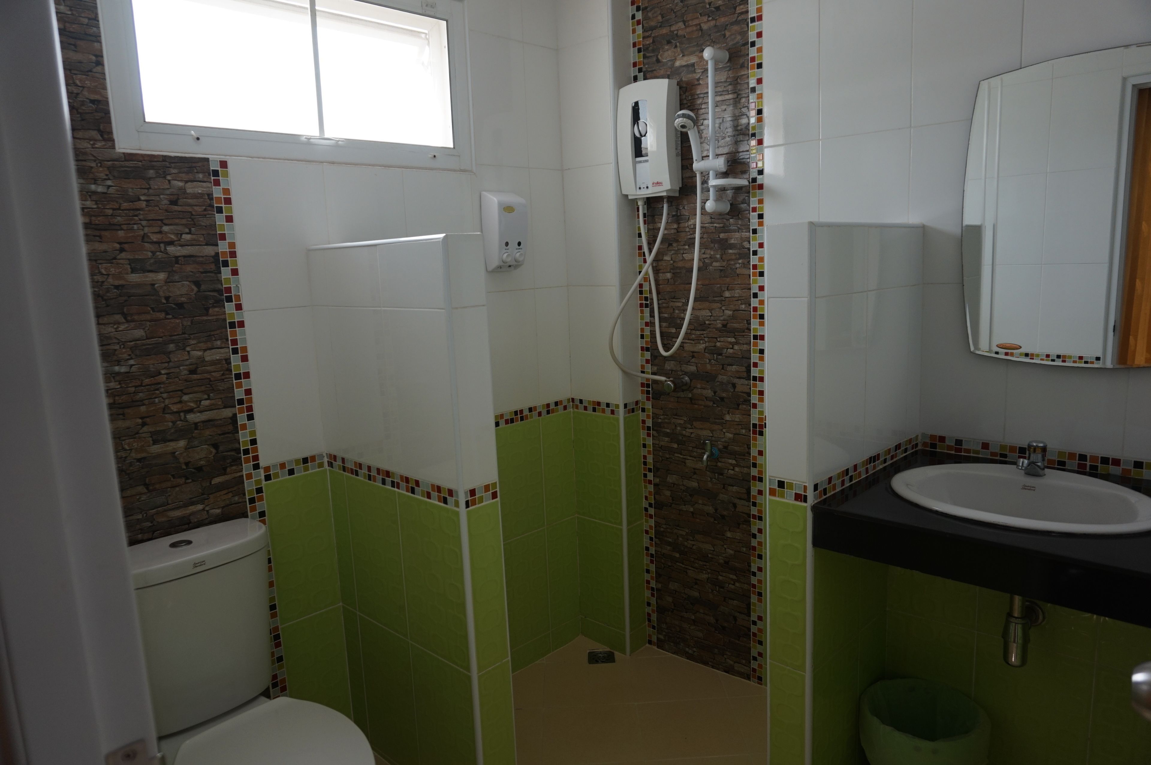 A bathroom with a toilet, a shower, a sink, and a mirror.