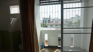 Habitación con vista a un paisaje urbano a través de una ventana con barrotes, un inodoro y una zona de ducha.