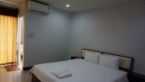 Habitación de hotel con cama, mesita de noche, aire acondicionado y una puerta con cortinas.
