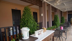 Zona de bar con una máquina de café, frascos de condimentos y asientos al aire libre.