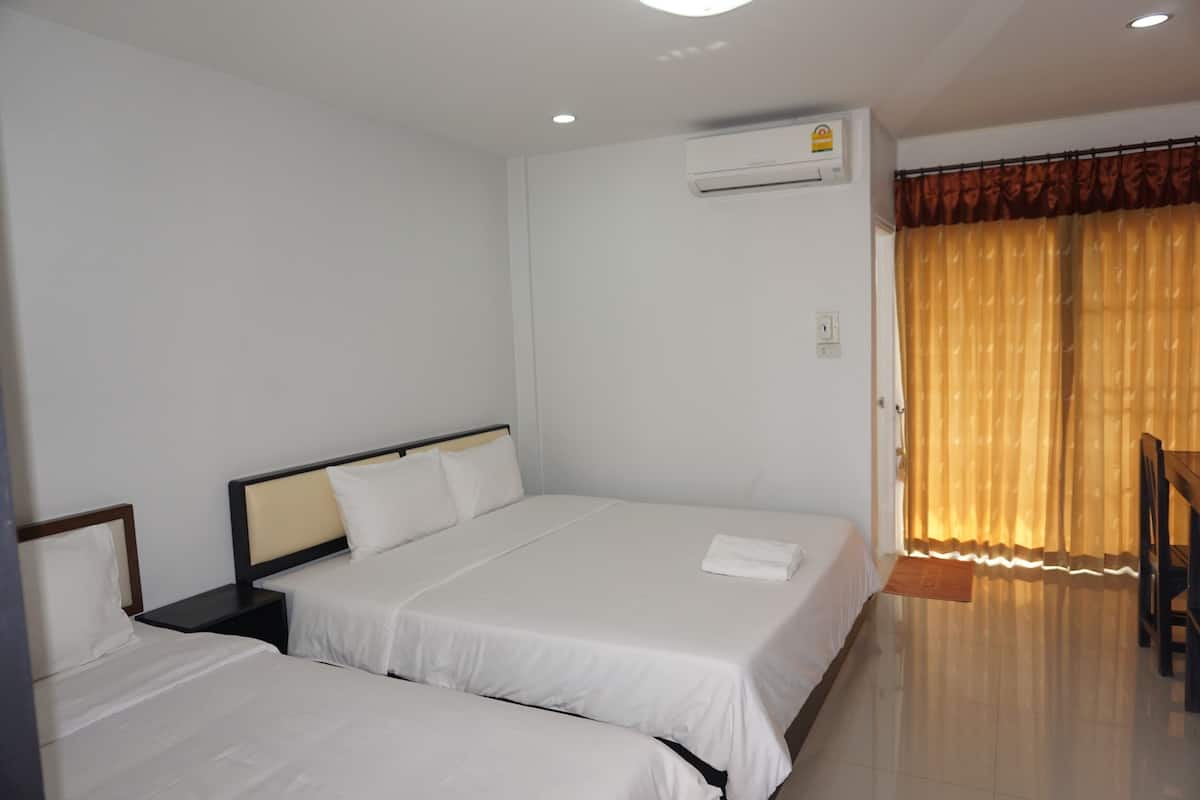 A hotel room with two single beds, a small table, and a chair.