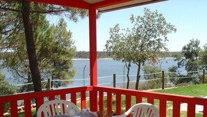 Un área de estar techada al aire libre con una mesa y sillas, con vista a un cuerpo de agua.