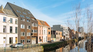 Un edificio a orillas de un canal, con varios pisos, techo plano y una combinación de estilos arquitectónicos de ladrillo y modernos.