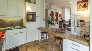Una cocina moderna con armarios blancos, horno integrado y salpicadero de azulejos.