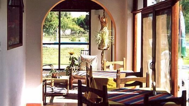 Un coin repas avec une table et des chaises, une plante en pot et une vue à travers une fenêtre en arc de cercle.