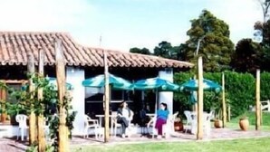 Un bâtiment doté d’un toit en tuiles et d’un espace extérieur abrité avec des parasols, aménagé pour accueillir des clients.