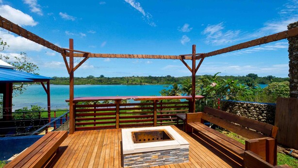 Une terrasse en bois avec un foyer, des bancs en bois et une vue sur un lac.