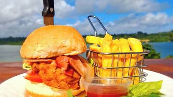 A meal consisting of a burger, fries, and a side of ketchup, with a knife on the table.