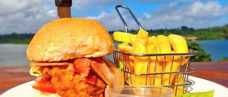 A meal consisting of a burger, fries, and a side of ketchup, with a knife on the table.