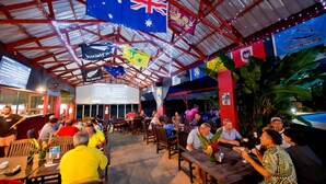 Un restaurant avec un plafond haut, des drapeaux suspendus au plafond et des tables dressées pour le dîner.