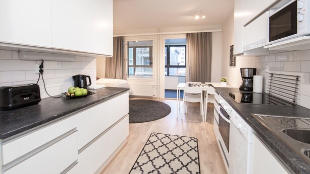 A modern kitchen with white cabinets, a black countertop, and a built-in microwave.