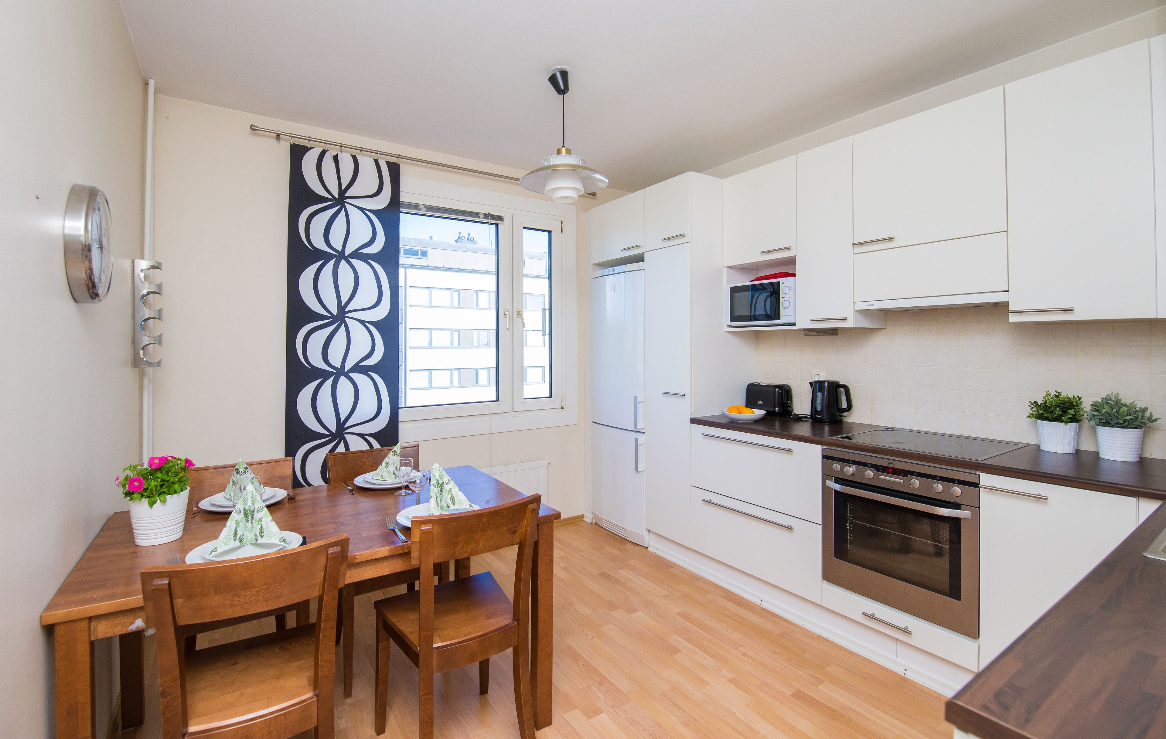 A modern kitchen with white cabinets, a wooden dining table, and a built-in oven.