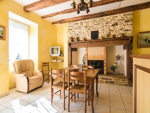 A cozy living room with a stone fireplace, wooden furniture, and a television on a shelf. - Beautiful holiday home near lake and forest (Savignac-Ledrier)