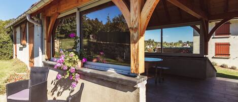 An outdoor patio area with wicker chairs, a table, and a view of the surrounding landscape.