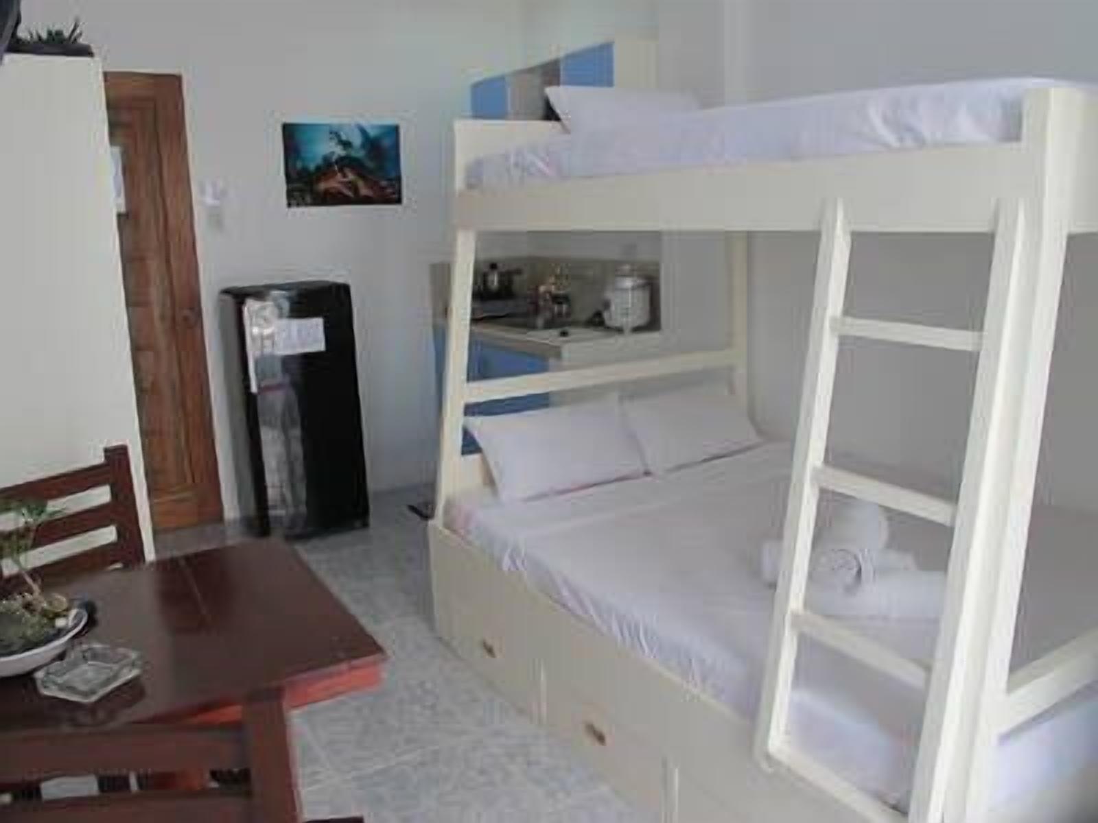 A bunk bed with a desk and chair, a small table with a plant, and a picture on the wall.