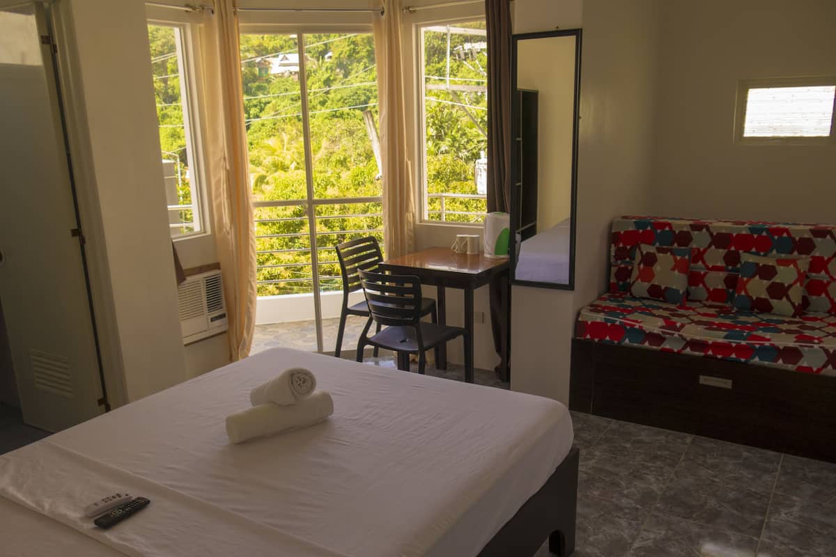 A hotel room with a bed, a desk, and a sofa.