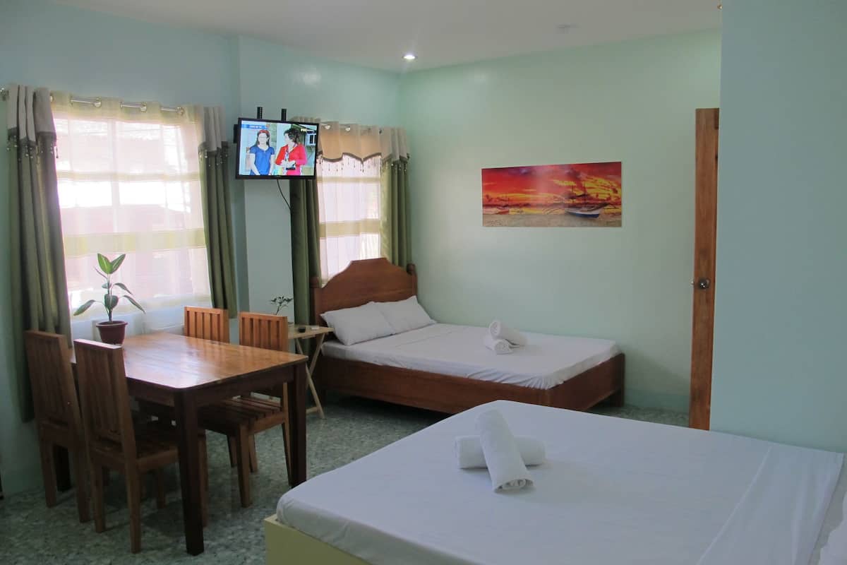 A hotel room with a bed, a desk, a chair, a television, and a painting on the wall.