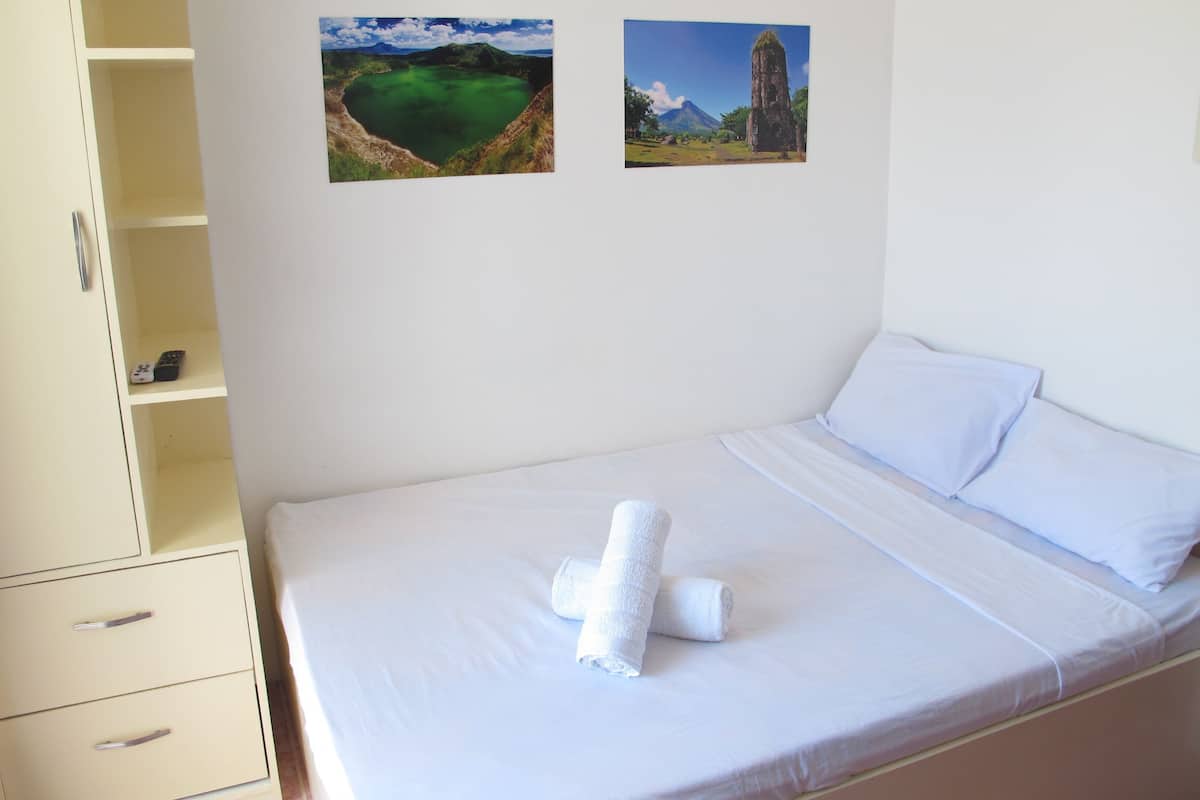A bedroom with a bed, a wardrobe, and two landscape pictures on the wall.