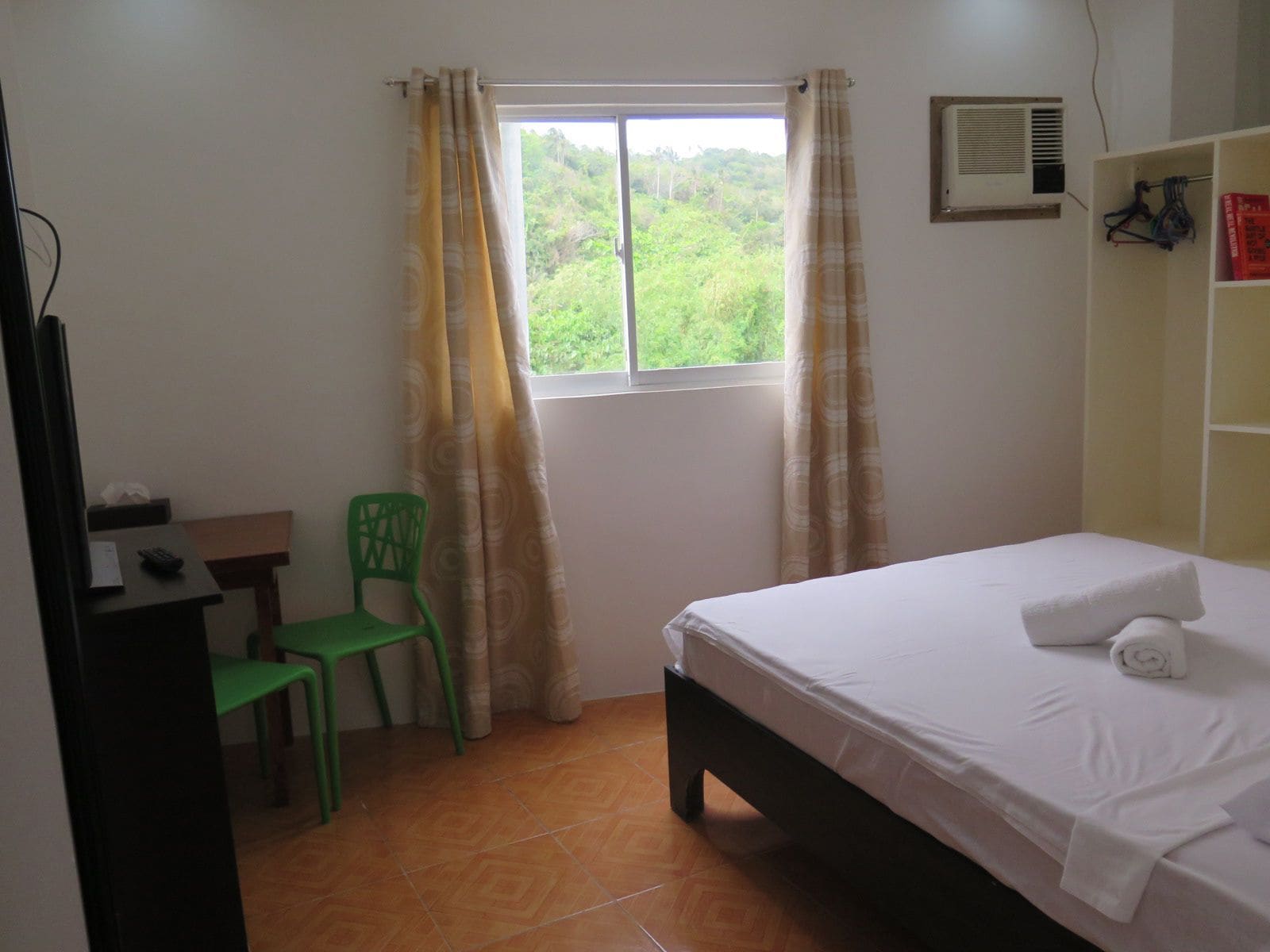 A small, clean room with a bed, a desk, a chair, and a window with curtains.