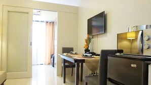 A hotel room with a dining area, a TV mounted on the wall, and a refrigerator. - Oceanblue Manila Condotel Sea Residences (Pasay)