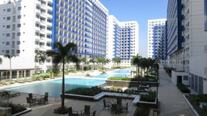A modern hotel with multiple floors, a central swimming pool, and outdoor seating areas. - Oceanblue Manila Condotel Sea Residences (Pasay)