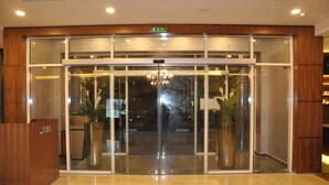 A hotel entrance with a revolving door, potted plants, and a reception desk. - Fortune Park Hotel (Dubai)