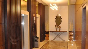 A modern lobby with a marble floor, wooden paneling, a reception desk, and a mirror. - Fortune Park Hotel (Dubai)