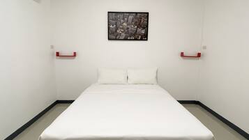 Ein schmales Hotelzimmer mit Bett, weißen Wänden und einem Stadtbild an der Wand.
