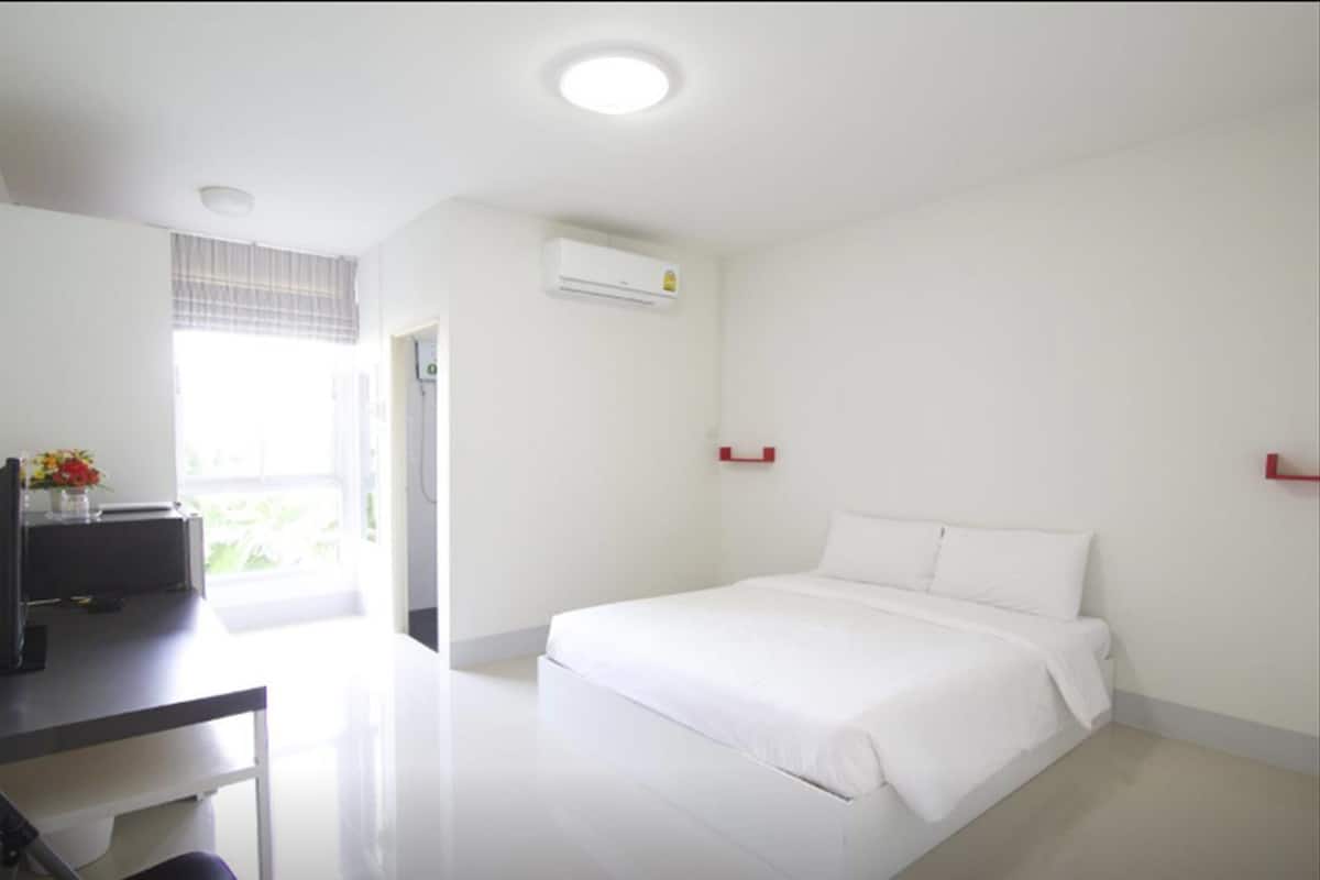 Ein modernes, minimalistisches Hotelzimmer mit einem großen Bett, einem Schreibtisch und einem Fenster, das für natürliches Licht sorgt.