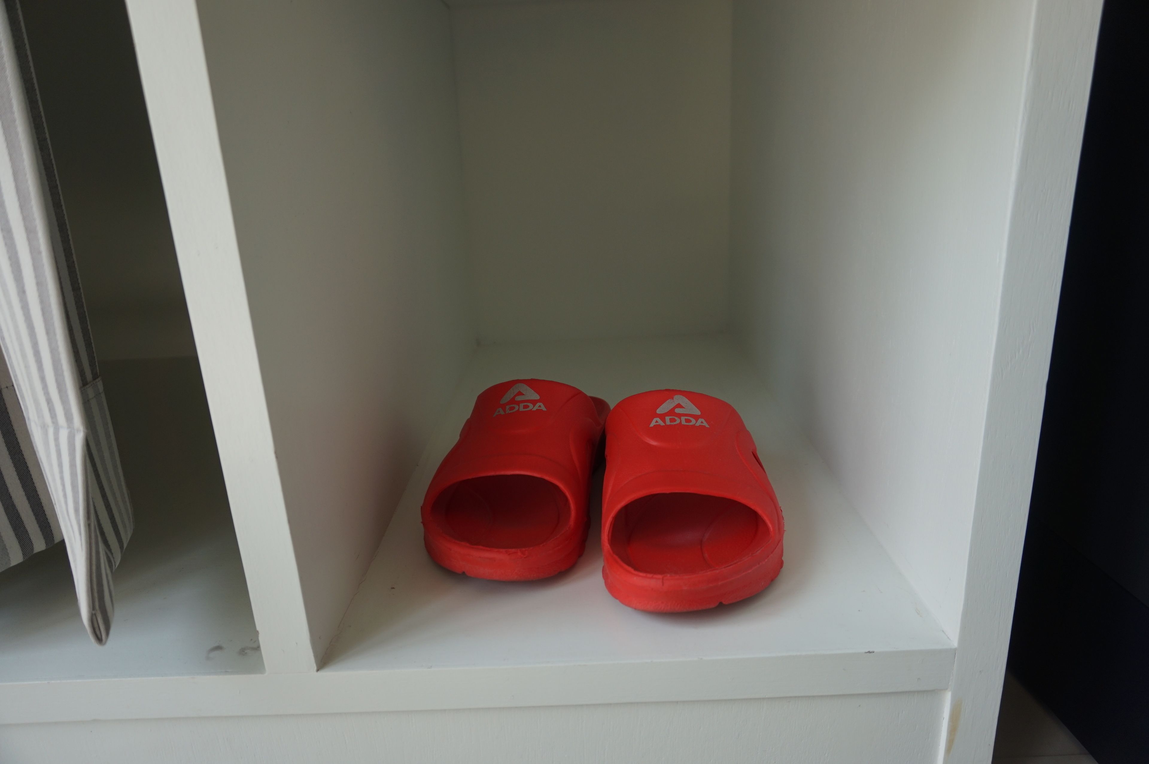 Un estante blanco con un par de pantuflas rojas.