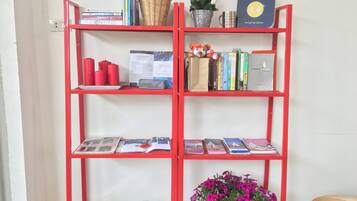 Een rode boekenkast met reisbladen, een kleine kerstboom en een plant in pot.