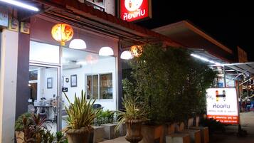 Un restaurante con terraza, plantas en macetas y un letrero en idioma extranjero.