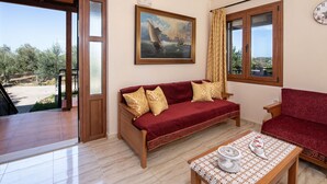 A living room with a red sofa, a wooden coffee table, and a painting of a sailboat.